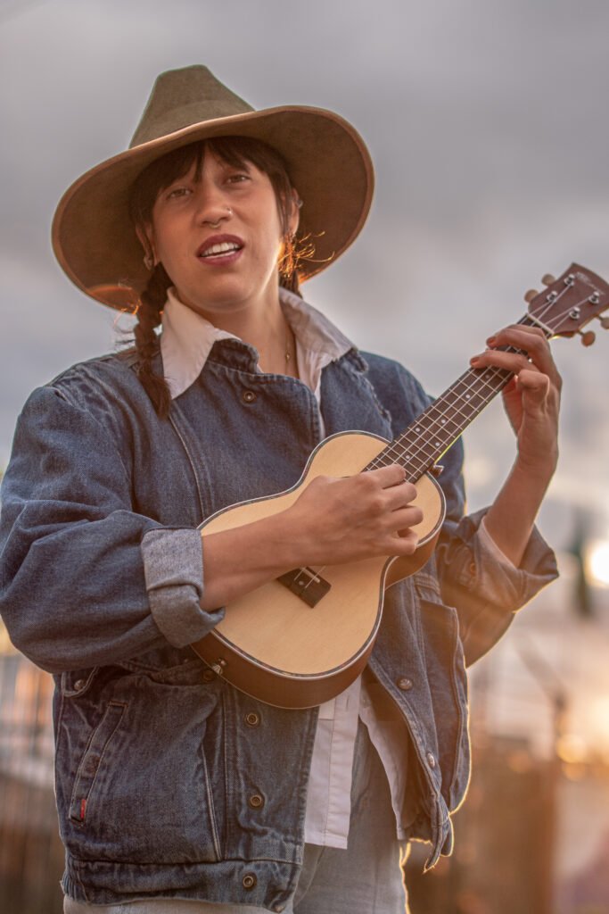 Artista con sombrero tocando ukelele al atardecer