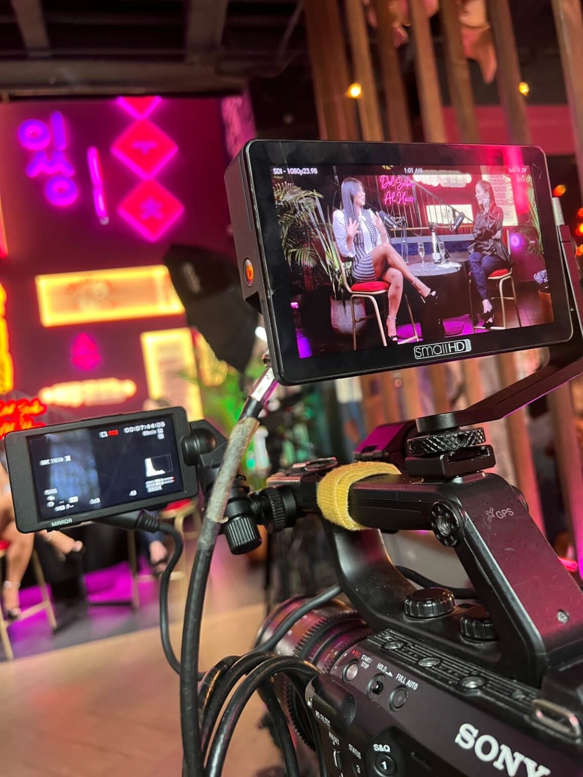 Cámara de cine y monitor en un set de podcast con luces neón